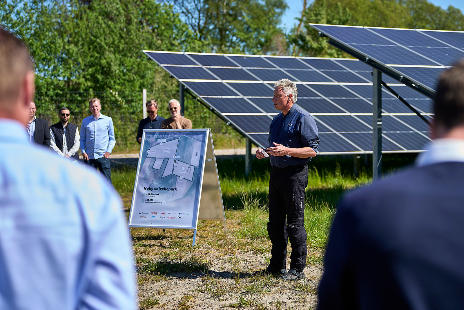 Image of a man speaking in front of solar panels