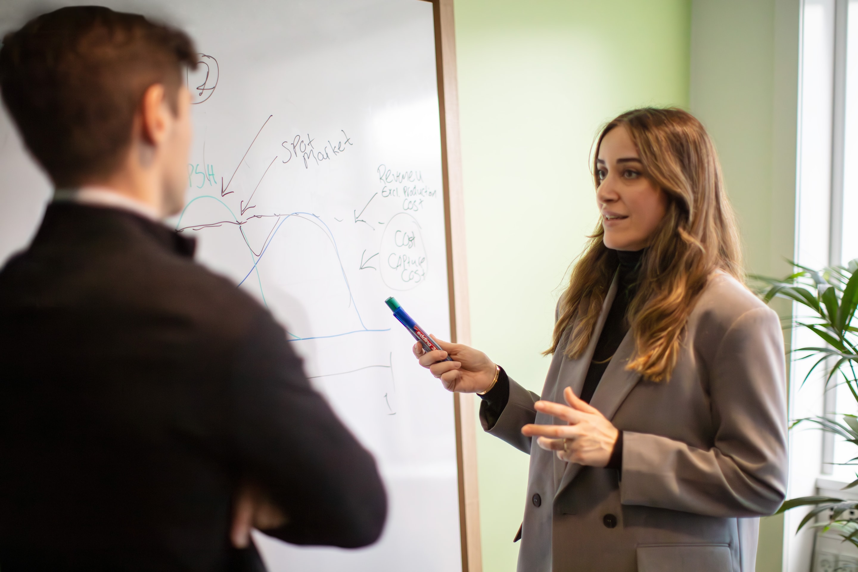 Two people discuss a drawing on a whiteboard